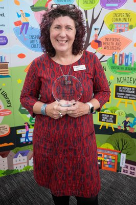 Helen Ackroyd who has dark hair and is wearing a red dress holding an award