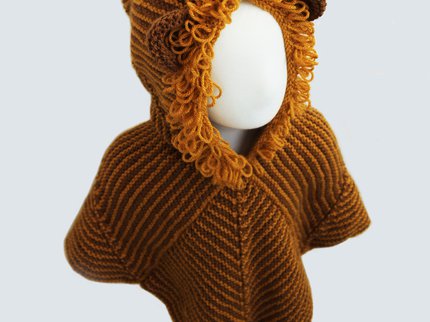 A picture of a child size mannequin wearing a hand knitted Story Snuggler with a hood