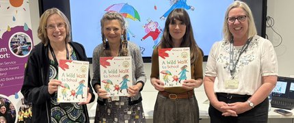 A photo of four women standing in a row holding books