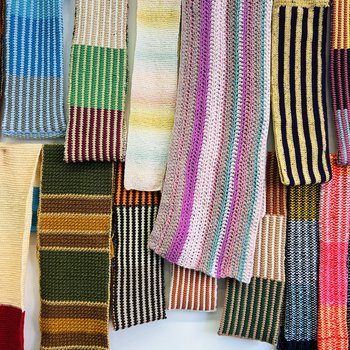 Close up of colourful knitted scarves hanging from a wall