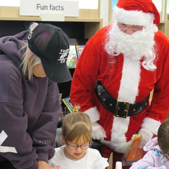 Child doing a craft while Santa supervises