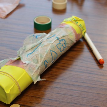 A rain stick made from a cardboard tube, paper and elastic bands