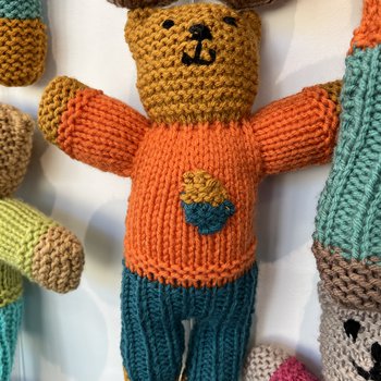 A hand knitted Brave Bear with an orange jumper