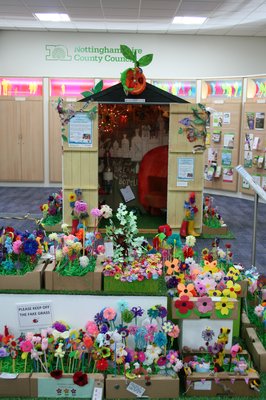 A wooden shed surrounded by boxes of craft flowers