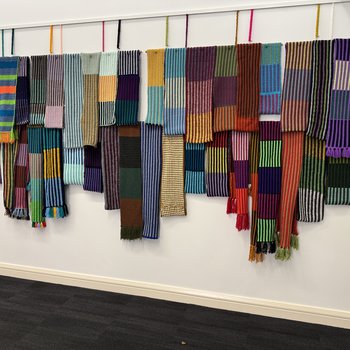 Close up of colourful knitted scarves hanging from a wall