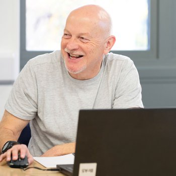 male learner at a laptop smiling