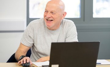 male learner at a laptop smiling