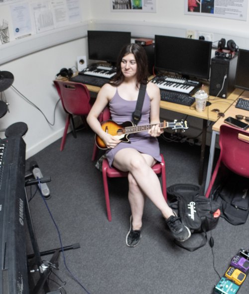 A young woman sat on a chair with a guitar