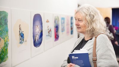 Lady looking thoughtfully at I am a Reader exhibition holding book