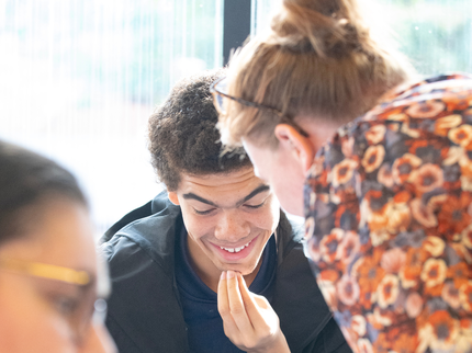 We see a smiling student looking at his GCSE results with his teacher