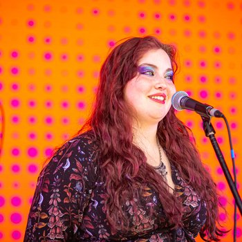 A girl with colourful eye makeup singing into a microphone