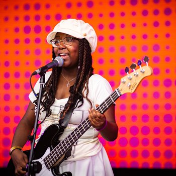 A young girl in a white dress playing guitar on stage