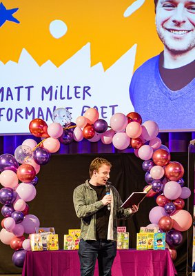 Matt Miller on stage reading a poem