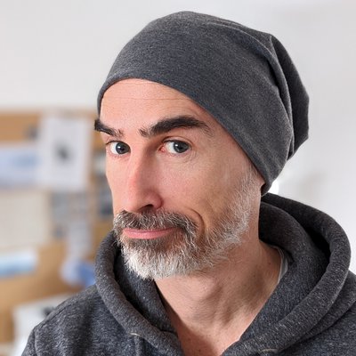 A picture of James Davis - author. He is a middle-aged white man wearing a grey hoodie and a beanie hat