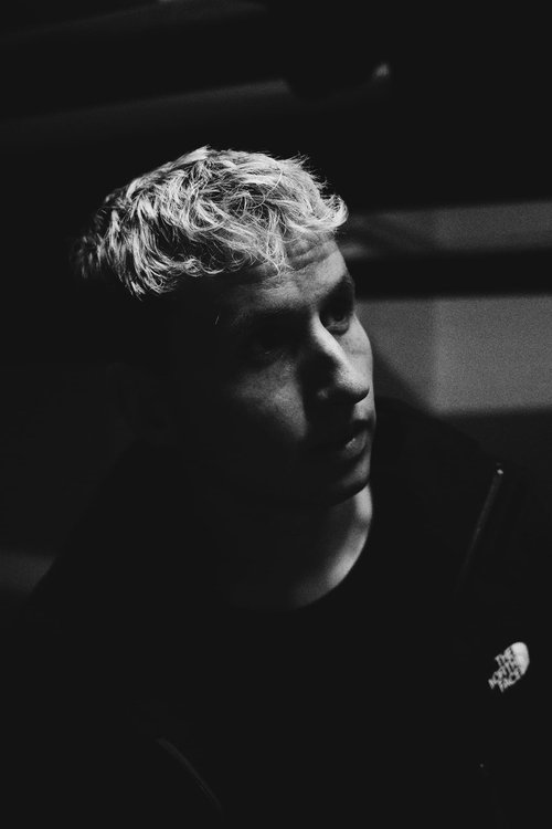 A black and white headshot image of a man with blonde hair.