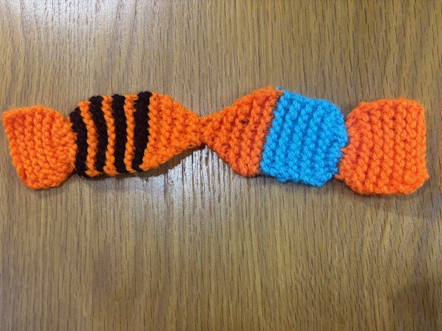 A knitted bookmark shaped like two kissing fish