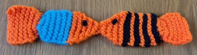 A knitted bookmark shaped like two fish, kissing