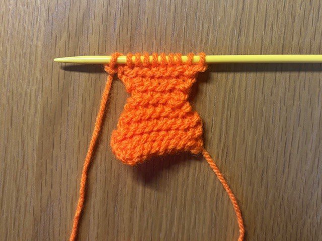 A piece of knitting showing decreasing and increasing to make a fish tail shape