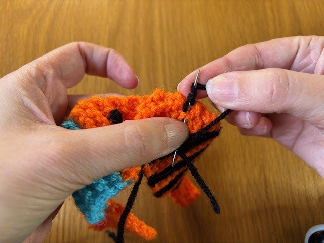 A piece of yarn wrapped three times around a sewing needle