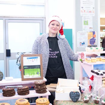 Stallholder smiling behind a stall full of cakes and sweet treats