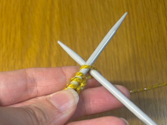 Knitting needle going through the first stitch in a row