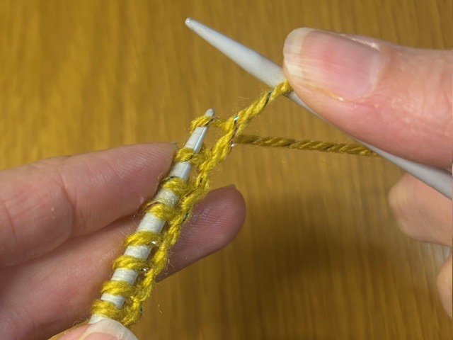 Photo of a knitting stitch being slipped off a needle