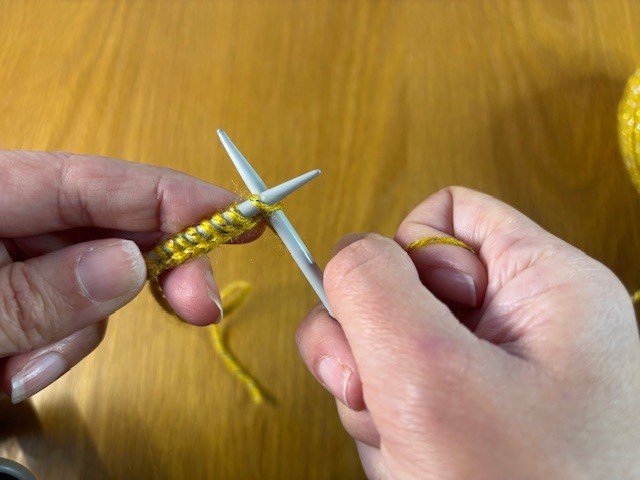 Imagine of knitting needle going through the first stitch in a row