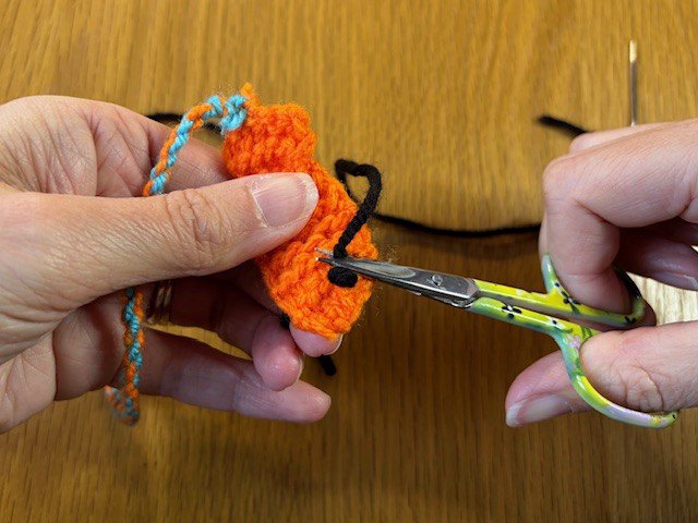 A pair of scissors snipping off a yarn tail
