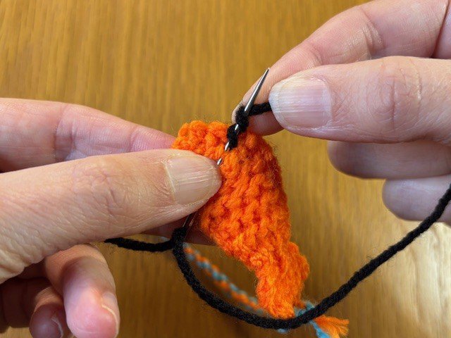 Yarn wrapped twice around a sewing needle