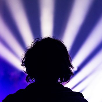 Shadow of a back of a man's head with purple light projections in front.