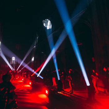 Church interior lit up red. Shadows of people in front.