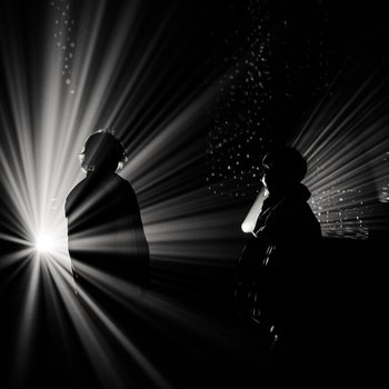Dark shadows of two people in front of a light projection.