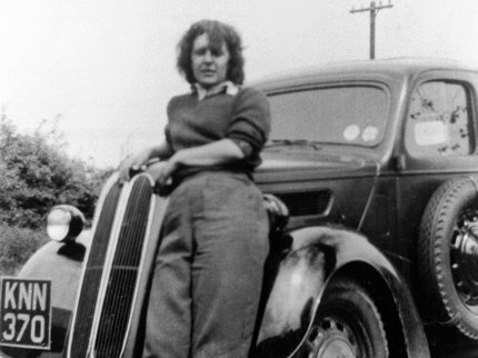 Land army girl leaning on a car on a farm at Collingham c. 1944