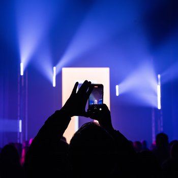 Back of head crowds with hands holding mobile phone