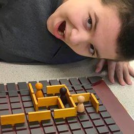 A child with short dark hair leans down over a board game.
