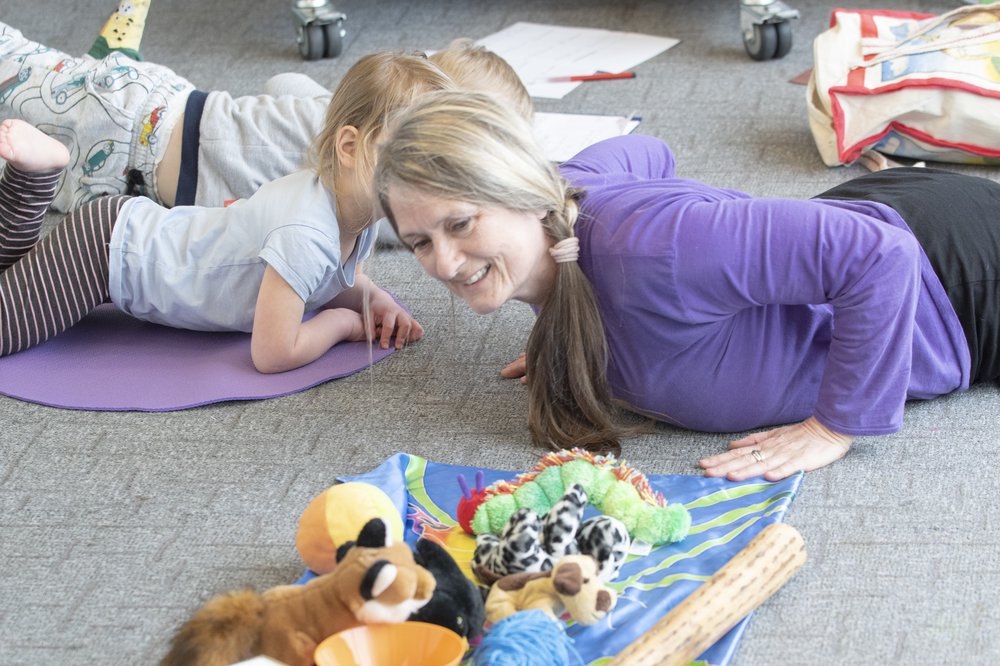 Female group leader doing yoga and creative activities with 2 young children