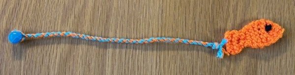 A small knitted fish on the end of a twisty string, with a bead on the end.