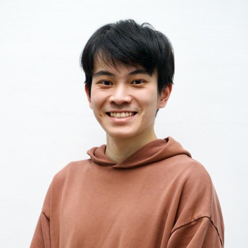 A headshot image of a man with dark hair wearing a brown hoodie smiling to the camera.