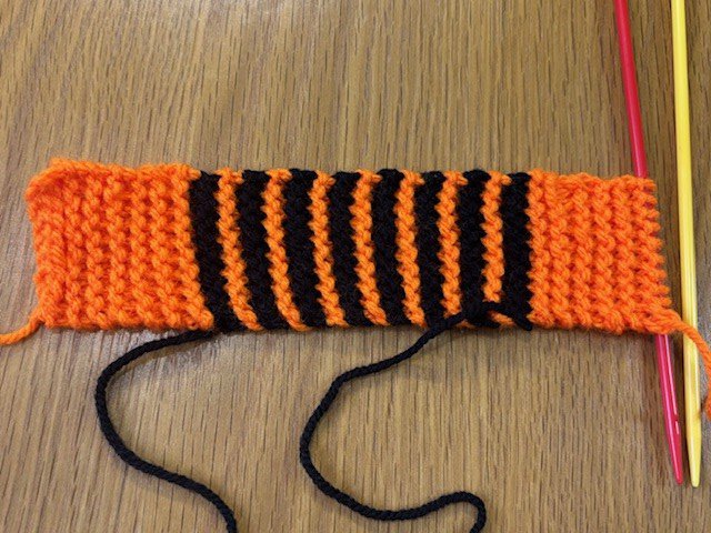 An orange and black striped knitted rectangle