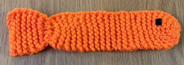 A knitted bookmark shaped like an elongated fish