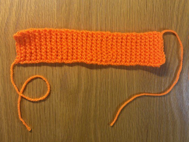 A knitted rectangle of orange yarn