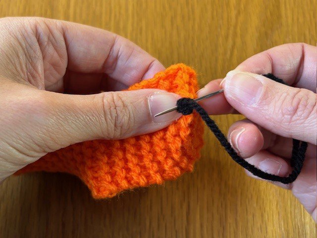 A sewing needle adding stitches behind a French knot