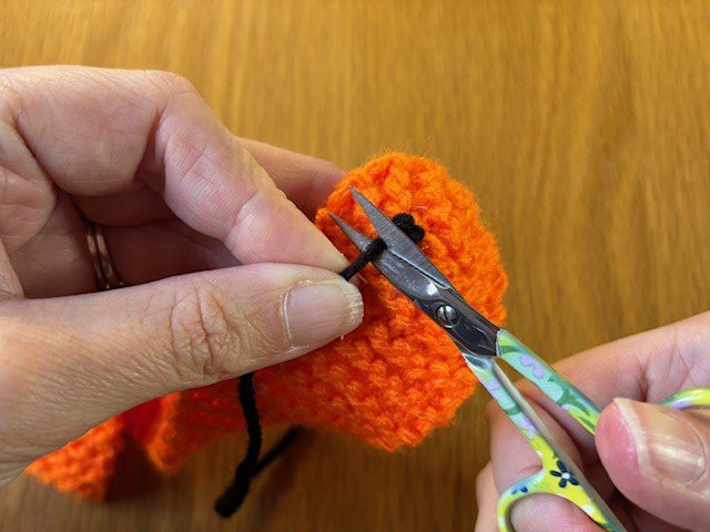 Scissors trimming a trailing yarn tail