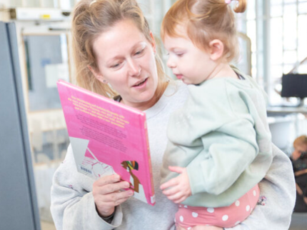 Parent and child at the self service kiosk together looking at books