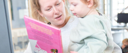 Parent and child at the self service kiosk together looking at books