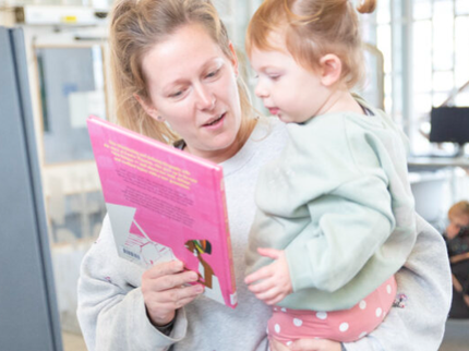 Parent and child at the self service kiosk together looking at books