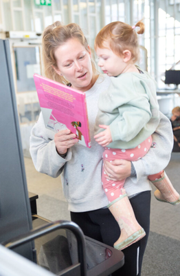 Parent and child at the self service kiosk together looking at books