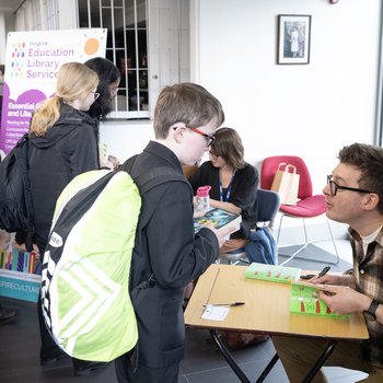 A group of authors stand in the mobile library van holding copies of their books