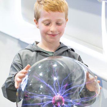 boy with hands on plasma ball