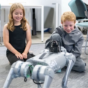 Boy and girl watching and smiling at robot dog